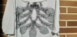 Camiseta blanca con pedrería morada y verde.