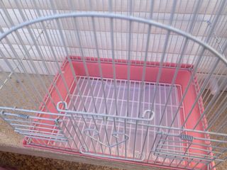 Jaula para pájaros rosa y plateada.