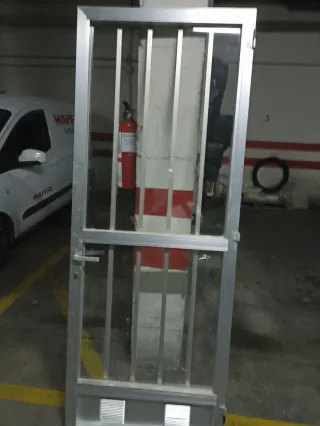 Puerta de aluminio con rejas y cristal