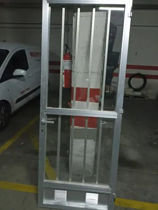 Puerta de aluminio con rejas y cristal