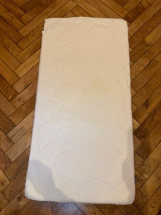 Cuna blanca, colchón y muchos accesorios de cama.