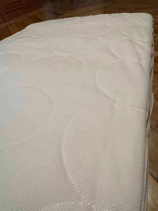 Cuna blanca, colchón y muchos accesorios de cama.