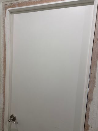 Puerta lacada en blanco con manivela.