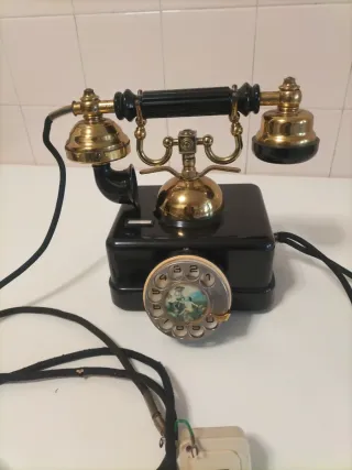 Teléfono antiguo de disco dorado y negro