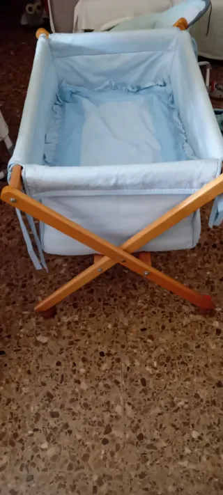 Minicuna azul con estructura de madera y ruedas