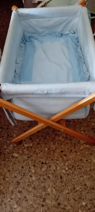 Minicuna azul con estructura de madera y ruedas