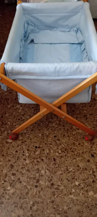 Minicuna azul con estructura de madera y ruedas