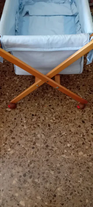 Minicuna azul con estructura de madera y ruedas
