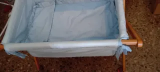 Minicuna azul con estructura de madera y ruedas