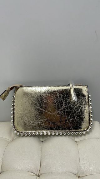 Bolso de mano dorado con tachuelas