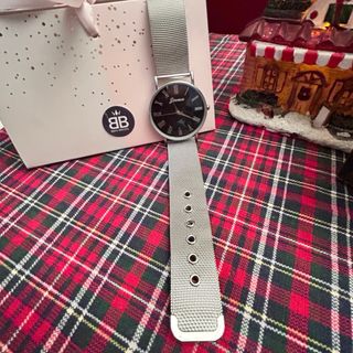 Reloj de bisutería color plateado y esfera negra.