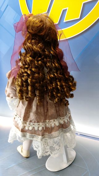 Muñeca de porcelana con gafas y vestido con encajes.