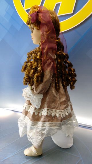 Muñeca de porcelana con gafas y vestido con encajes.