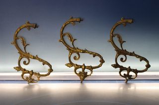 Tres apliques, tiradores, asas o adornos de bronce o latón.