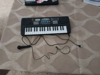 Teclado infantil con micrófono y cargador.