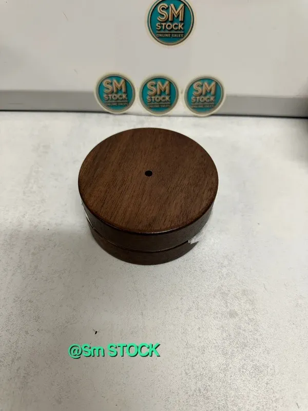 Cenicero de madera de nogal con un diseño elegante y un toque decorativo. Incluye una tapa y un pequeño adorno. - Material: Madera de nogal y metal. - Color: Marrón oscuro y dorado. - Diseño: Cil...