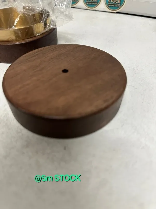 Cenicero de madera de nogal con un diseño elegante y un toque decorativo. Incluye una tapa y un pequeño adorno. - Material: Madera de nogal y metal. - Color: Marrón oscuro y dorado. - Diseño: Cil...