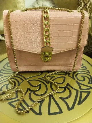 Bolso de mano rosa con cadena dorada