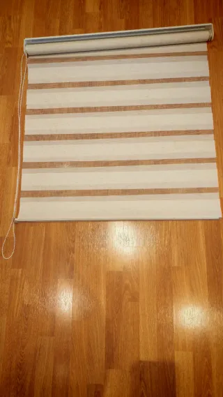 Tenda a rullo a righe beige e trasparente.