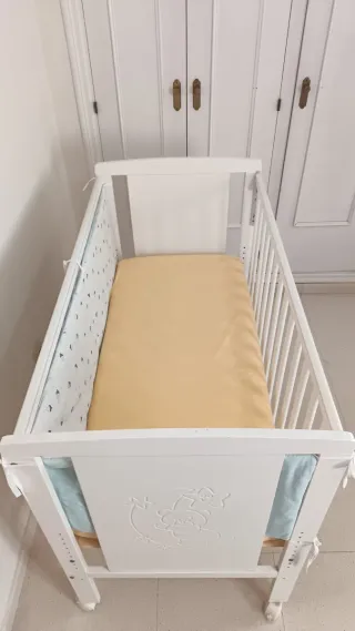 Cuna blanca con colchón de triple funda.