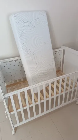 Cuna blanca con colchón de triple funda.
