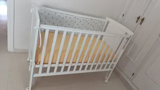 Cuna blanca con colchón de triple funda.
