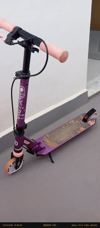 Patinete morado con ruedas naranjas