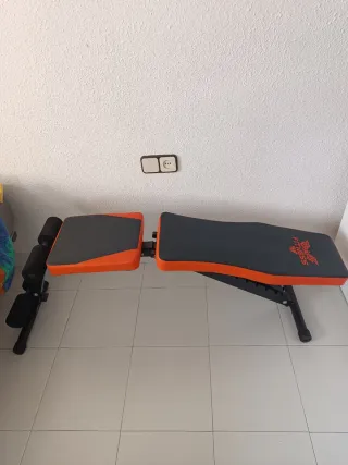 Banco de pesas ajustable naranja y negro.