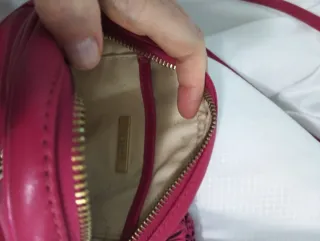 Bolso Uterqüe redondo color fucsia y ribete dorado