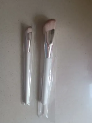 Brochas de maquillaje plateadas y blancas, crema