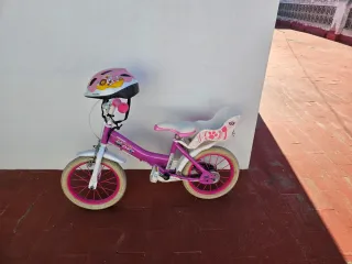 Bicicleta infantil rosa con casco junto con patín
