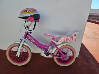 Bicicleta infantil rosa con casco junto con patín