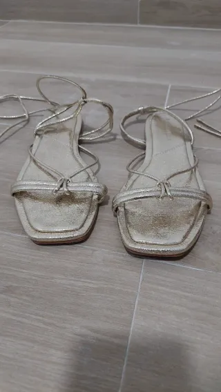 Sandalias doradas atadas en tobillo