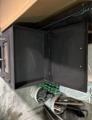 Chimenea de leña negra con puerta de cristal