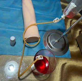 Brazo simulador enfermería con herramientas