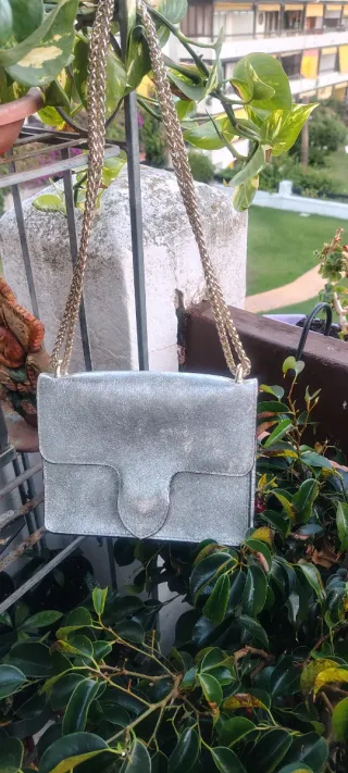 Bolso de mano plateado con cadena dorada