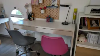 Escritorio blanco con sillas rosa y gris.