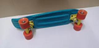Monopatín azul con ruedas naranjas