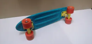 Monopatín azul con ruedas naranjas