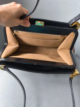 Bolso de cuero negro con logo dorado