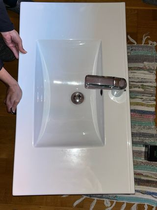 Mueble de baño gris con lavabo sin grifo.