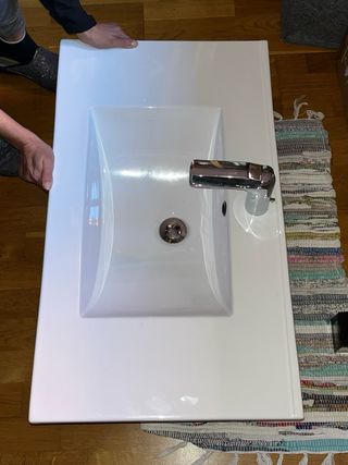 Mueble de baño gris con lavabo sin grifo.