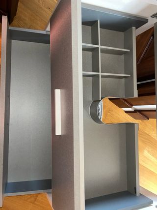 Mueble de baño gris con lavabo sin grifo.