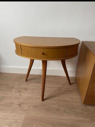 Mesita de noche de madera de forma ovalada.