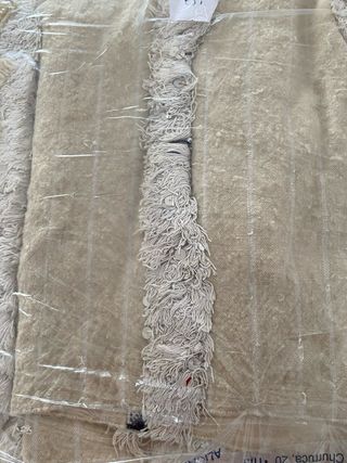 Alfombra beige con flecos y detalles