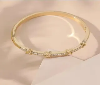 Pulsera dorada con cierre y detalles brillantes.