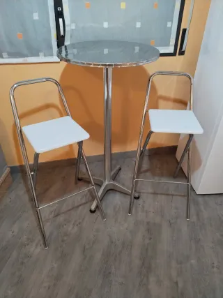 Mesa alta plateada con 2 sillas blancas