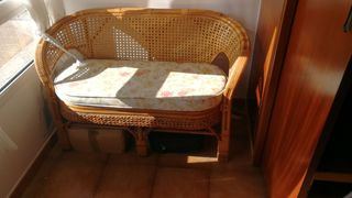 Sofá de ratán con cojín floral