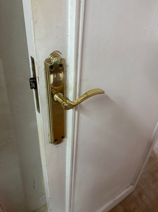 Puerta de madera blanca con manilla dorada