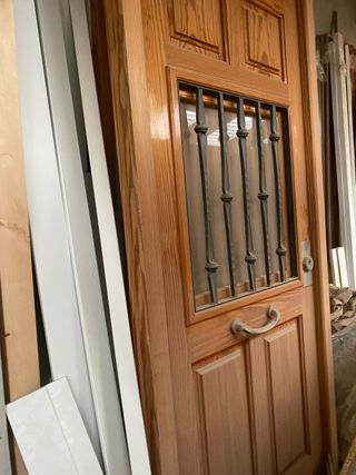 Puerta madera entrada con reja y postigo